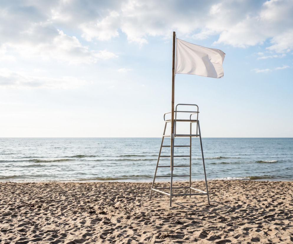Biała flaga na wieży ratowniczej na pustej plaży w Stegnie. O warunkach kąpieli przeczytasz na Eska Trójmiasto.