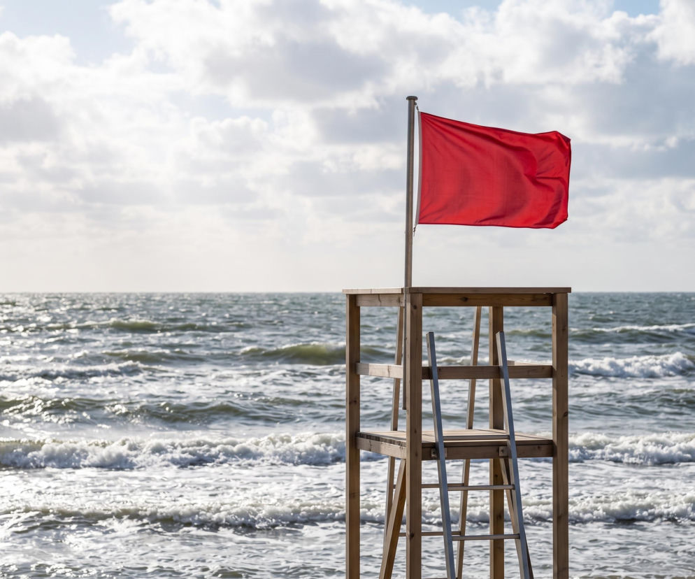 Czerwona flaga na wieży ratowniczej nad wzburzonym morzem. O zamkniętych plażach w Stegnie przeczytasz na Eska Trójmiasto.
