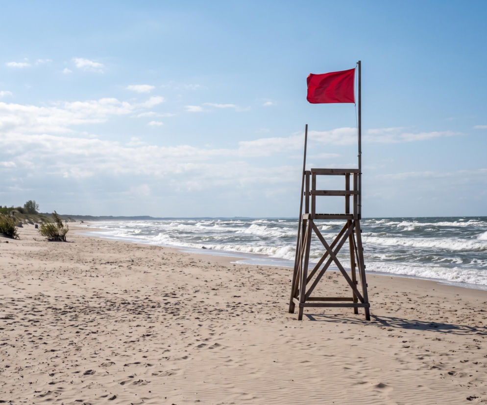 Czerwona flaga na wieży ratowniczej na pustej plaży w Świnoujściu. O zakazie kąpieli przeczytasz na SE Szczecin.