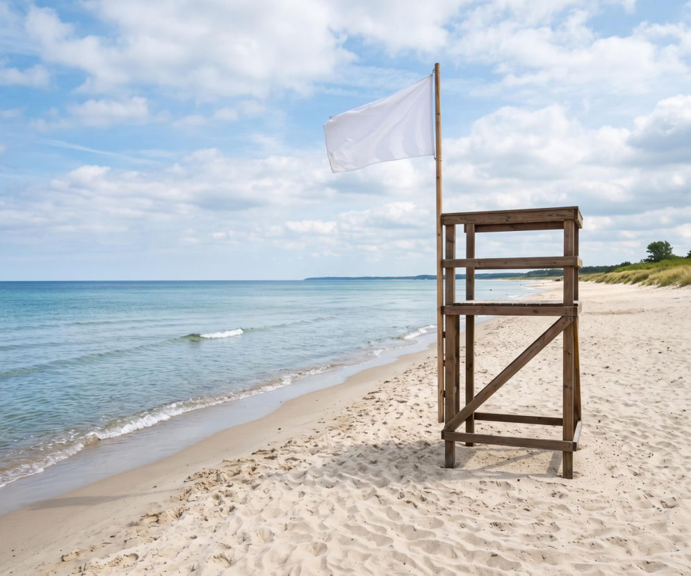 Drewniana wieża ratownika z białą flagą na pustej plaży. O bezpiecznych kąpielach w Świnoujściu przeczytasz na SE Szczecin.