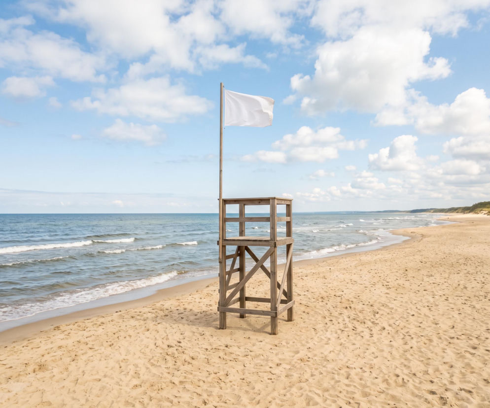 Biała flaga na wieży ratowniczej na pustej plaży w Trzęsaczu. O bezpiecznych kąpielach przeczytasz na SE Szczecin.