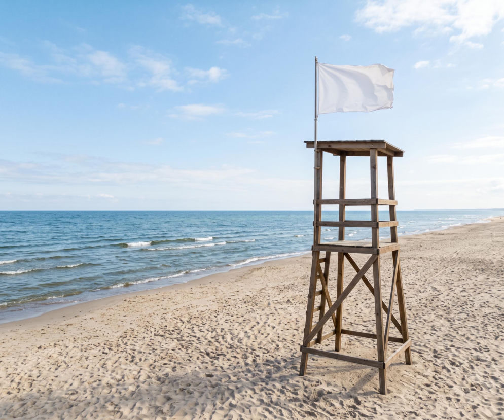 Biała flaga na wieży ratowniczej na pustej plaży w Ustce. O bezpieczeństwie w kąpieliskach przeczytasz na Eska Trójmiasto.
