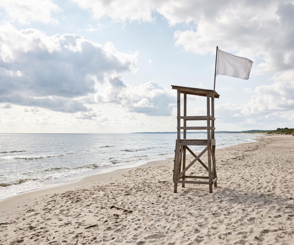 Biała flaga na wieży ratowniczej na pustej plaży w Ustroniu Morskim. O bezpieczeństwie kąpieli przeczytasz na SE Szczecin.