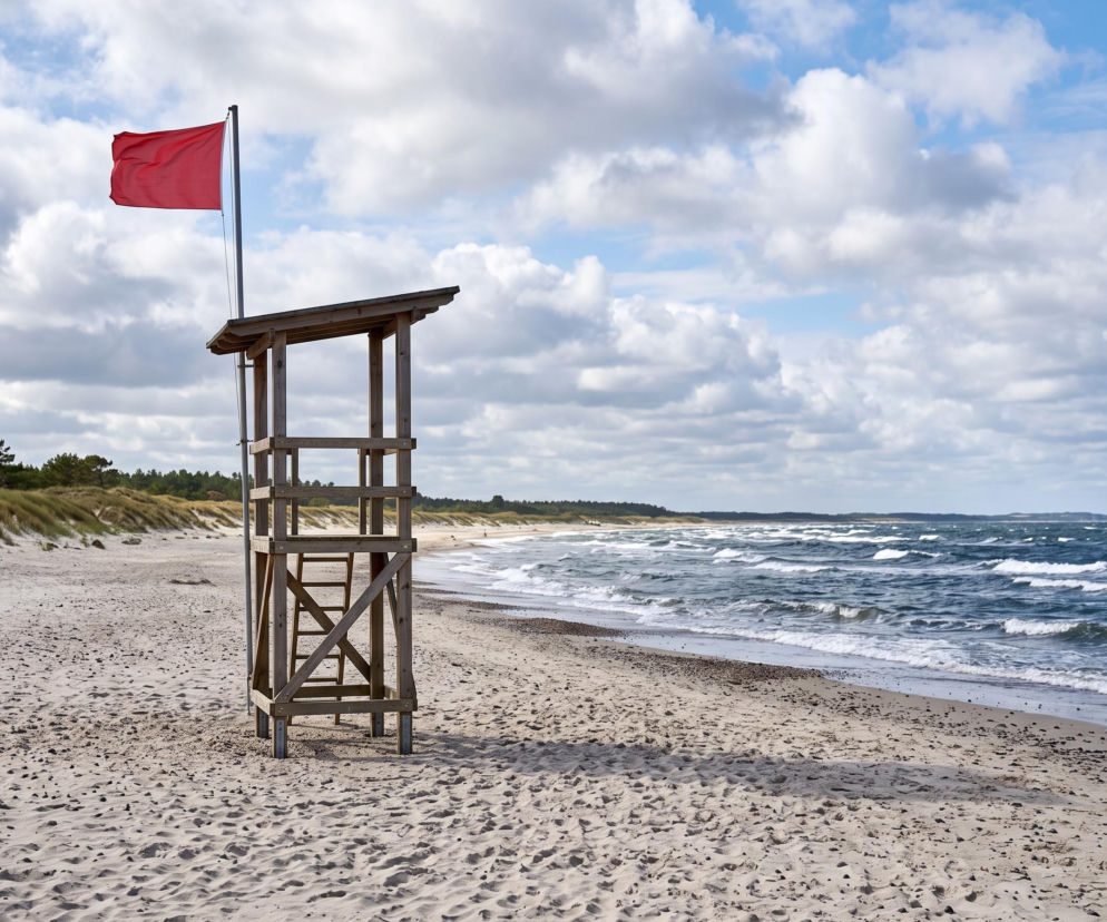 Czerwona flaga na wieży ratowniczej przy pustej plaży we Władysławowie. O zakazach kąpieli przeczytasz na Eska Trójmiasto.