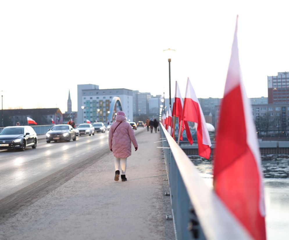Piesza idzie mostem granicznym w Słubicach przy polskich flagach. O zamknięciu mostu przeczytasz na Radioplus.