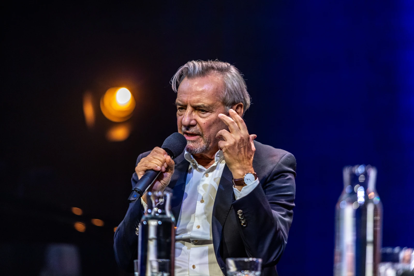 Mężczyzna w garniturze trzyma mikrofon i gestykuluje podczas wystąpienia. Autor: Bogusław Świerzowski