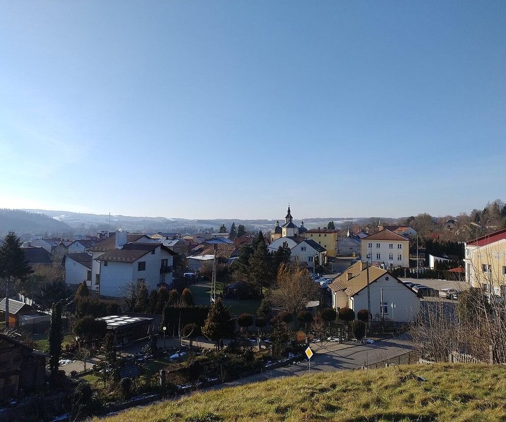 Panorama miejscowości Żołynia z widokiem na domy i kościół. O nowych miastach w regionie przeczytasz na Eska Rzeszów.