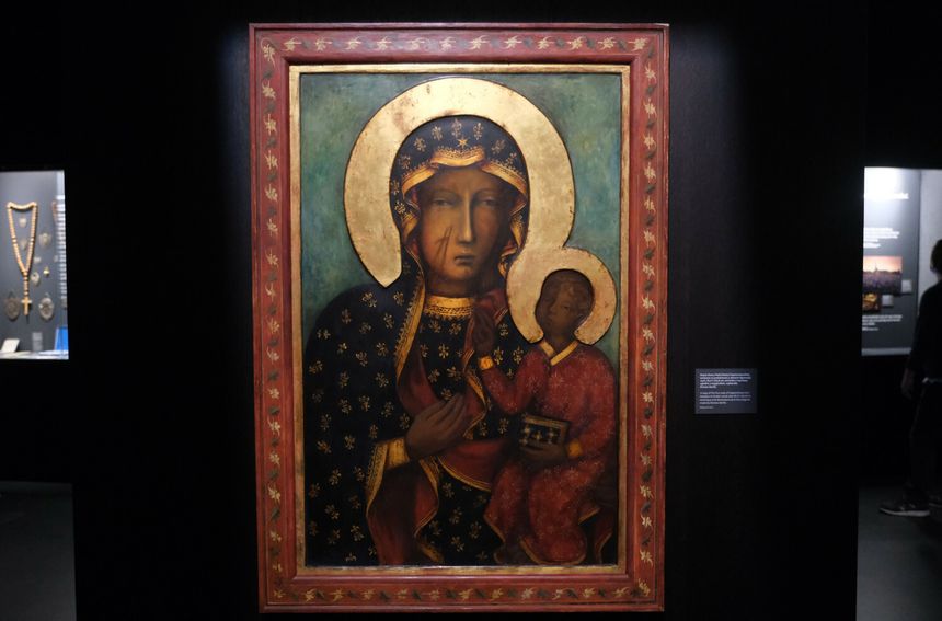 Ikona Matki Boskiej Częstochowskiej z Dzieciątkiem, z bogatymi zdobieniami, na ciemnym tle.