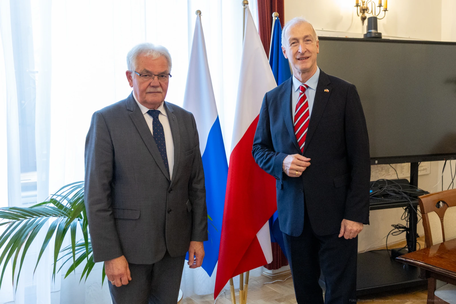 Dwaj mężczyźni stoją obok siebie, za nimi flagi Rosji i Polski. Autor: Bogusław Świerzowski
