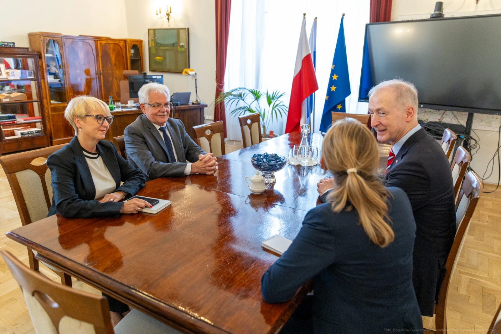 Spotkanie czterech osób w sali konferencyjnej z flagami Polski i UE w tle. Autor: Bogusław Świerzowski