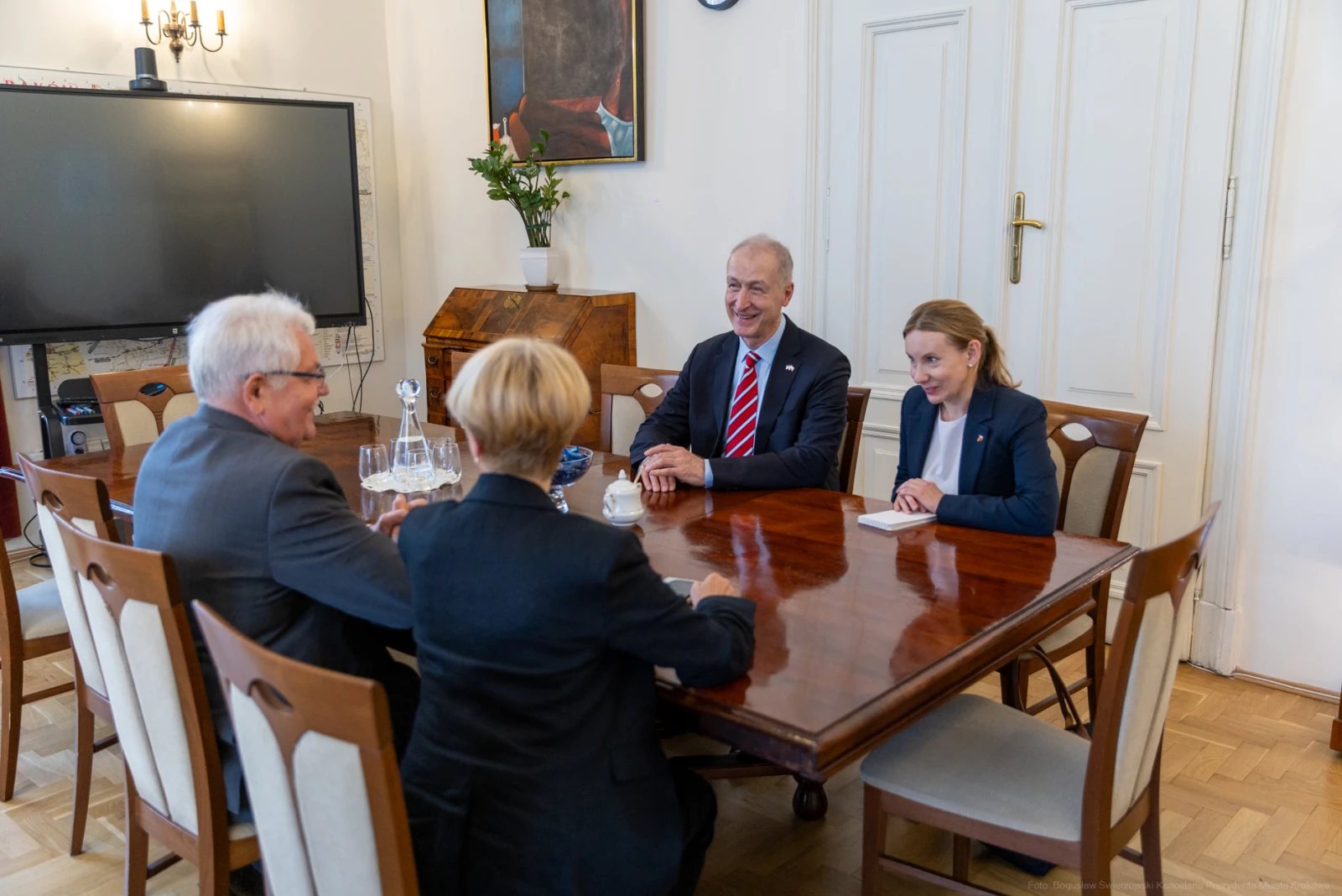 Spotkanie czterech osób przy stole w eleganckim wnętrzu. Autor: Bogusław Świerzowski