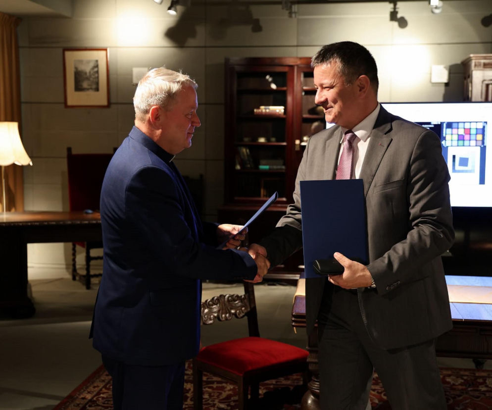 Ks. Stanisław Stelmaszek i prof. Artur Błażejewski podają sobie ręce. O współpracy uczelni i kościoła czytaj w Radioplus.
